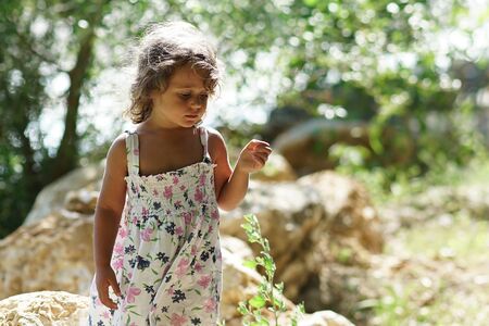 A blond girl of three years thoughtful near the Acheron River with its pristine nature in Epirus, Greeceの写真素材