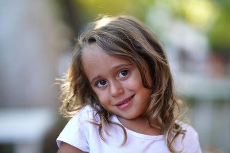 portrait of a very cute 4 year old girl who smiles and looks straight into the cameraの写真素材