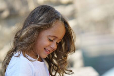 portrait of a beautiful 4 year old girl who smiles and looks down