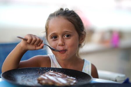 Adorable 4 year old girl eating a crÃªpes, smiling.の写真素材