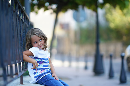 a beautiful 4-year-old girl leaning on a railing looks to the sideのeditorial素材