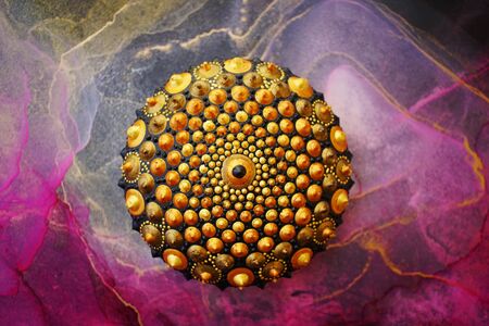 Beautiful hand painted mandala rock on alcohol ink background