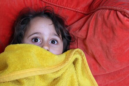 a 5 year old girl plays modeling with a yellow blanketの写真素材