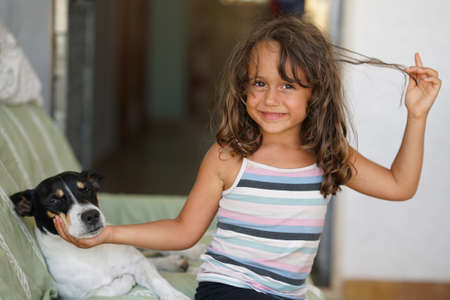 5 year old girl plays caresses her little dog and smilesの写真素材