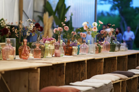 Beautiful decoration with flowers and colorful glass vases, selective focus