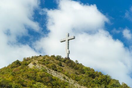 Popular sight of the Gelendzhik resort city. Worship cross on hill of Caucasian mountain against blue cloudy sky background.の写真素材