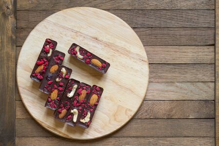 Raw foods healthy homemade chocolate sticks with almonds, cashews and raspberries, lie on a round...