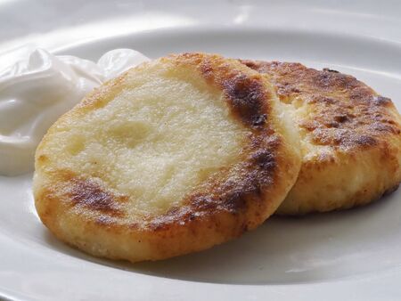 Toasted cottage cheese pancakes with a Golden crust lie on a white plateの写真素材