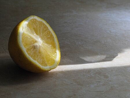 The sun's rays illuminate a fresh citrus slice on the kitchen tableの写真素材