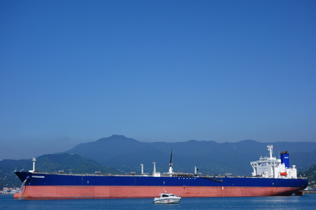 Batumi, Georgia - January 10, 2014 - Small Georgian Coast Guard patrol boat and a large size oil tanker Petrozavodsk floating in Black Sea and unloading water from its tanks while anchored outside oil terminal in Batumi, Georgia on a cloudless sunny day oのeditorial素材