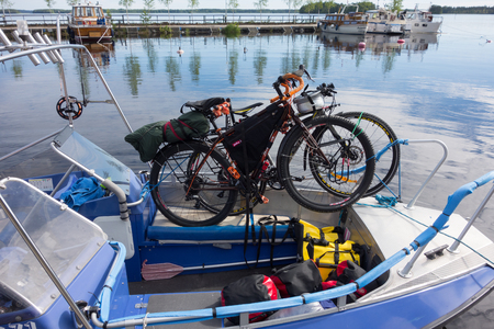 Taipalsaari, Finland â July 2, 2015:  Two touring bikes tied securely to a fishing boat with colorful panniers on the boat floor by the lake Saimaa, Finland for crossing to the other side of the lake from Taipalsaari on 2 July 2015.のeditorial素材