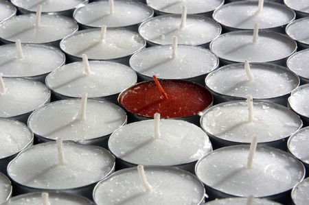 A group of white tea candles with a single red tea candle.の写真素材