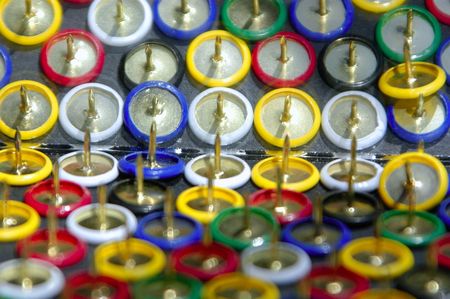 A group of colorful thumb tacks reflected in a mirror.