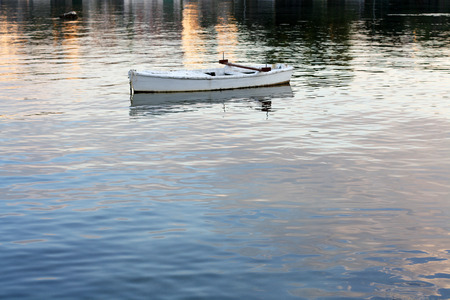 Small wooden boat in the sea during sunset.