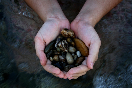 Hands holding stones in the river.の写真素材