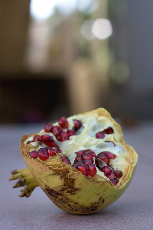 Sliced juicy organic pomegranate on the table, soft bokeh in the background.の写真素材
