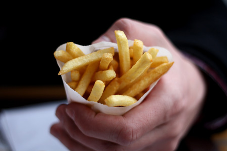 Hand holding small portion of French fries.の写真素材