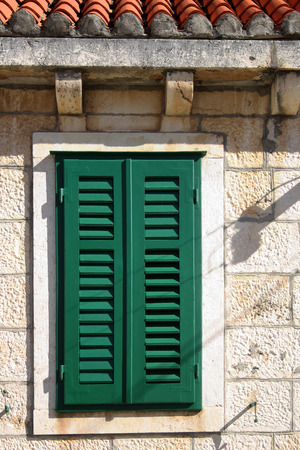 Architectural detail on a traditional mediterranean house: green window on a stone facade.の写真素材