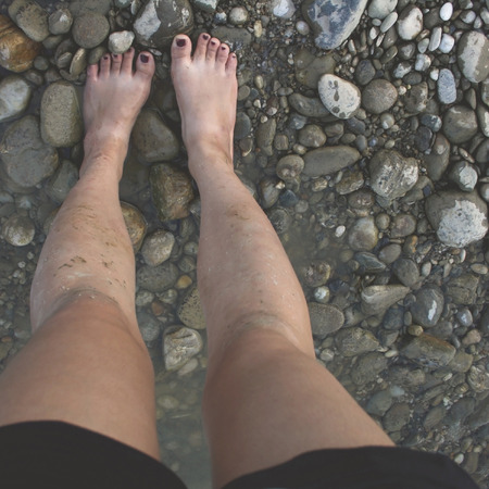 Female legs in the shoal, dirty from the water.の写真素材