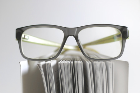 Hipster eyeglasses on the book. Selective focus, white background.の写真素材