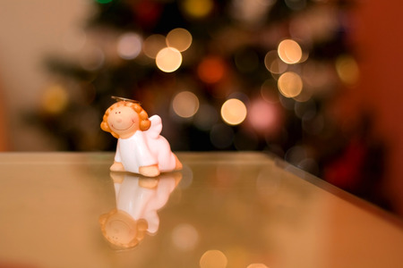 Little figurine shaped like an angel. Christmas tree bokeh in the background.の写真素材