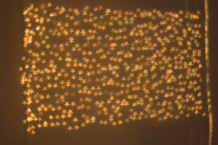 Shiny defocused background with bokeh lights shaped like little stars.