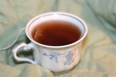 Cup of tea with tea bag on the bed.の写真素材