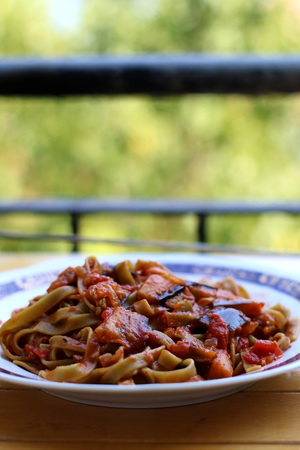 Plate of green pasta with sliced zucchini and tomato sauce. Selective focus, copy space.の写真素材
