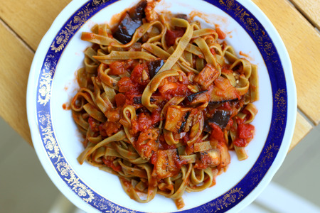 Plate of green pasta with sliced zucchini and tomato sauce. Top view.の写真素材