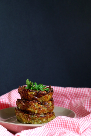 Hash browns made with shredded potato, parmesan and scallion. Decorated with parsley and mustard. Selective focus, black background.の写真素材