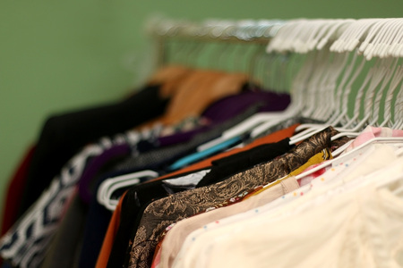 Colourful clothes on a clothes rack. Close-up, selective focus.の写真素材