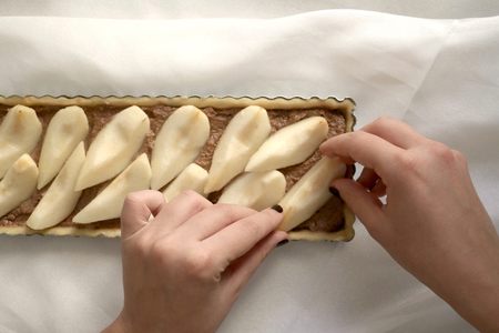 Unrecognizable person making a pear and almond tart. Top view.