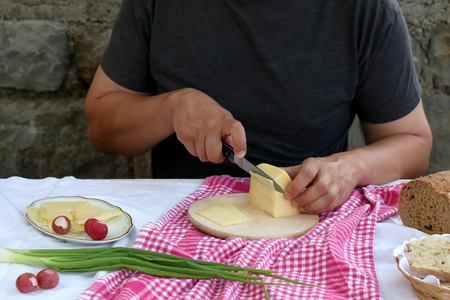 Unrecognizable person making breakfast, cutting bread and cheese. Selective focus.の写真素材