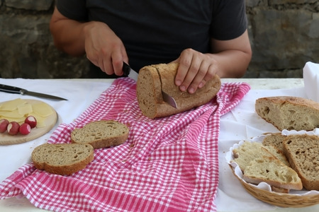 Unrecognizable person making breakfast, cutting bread and cheese. Selective focus.
