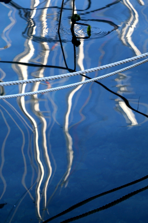 Rope above the sea surface, interesting reflections of boats in the sea. Selective focus.の写真素材