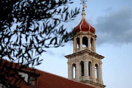 Historic bell tower in Sutivan, island Brac, Croatia. Selective focus, defocused olive tree in the foreground.の写真素材