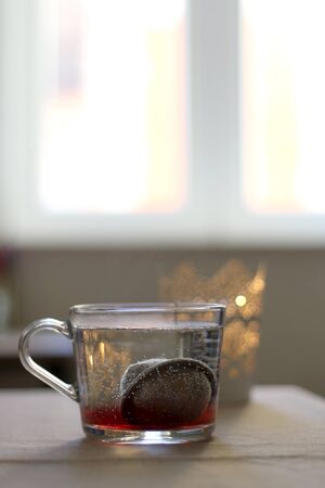 Cup of hot water with tea infuser. Candle holder in the background. Selective focus.の写真素材