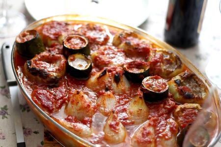 Pepper, onion and zucchini stuffed with various vegetables and roasted with tomato sauce, served on a table. Selective focus.の写真素材