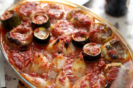 Pepper, onion and zucchini stuffed with various vegetables and roasted with tomato sauce, served on a table. Selective focus.の写真素材