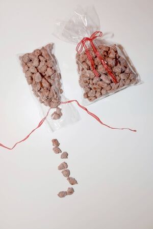 Two bags of homemade candied almonds with red ribbons on white background. Selective focus.の写真素材