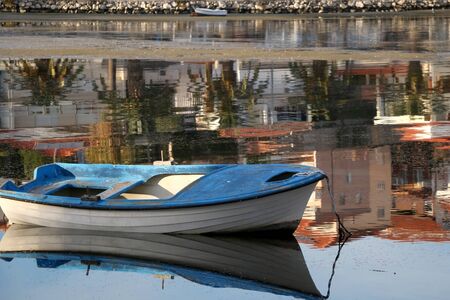 Small old fishing boat in a shallow sea. Colorful reflections in the background. Selective focus.の写真素材