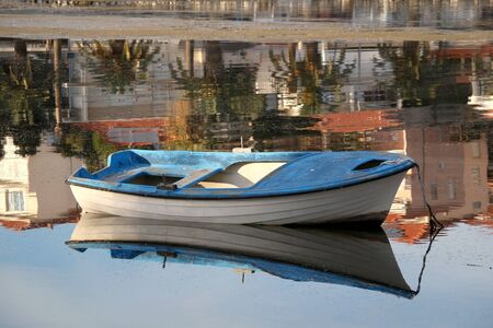 Small old fishing boat in a shallow sea. Colorful reflections in the background. Selective focus.の写真素材