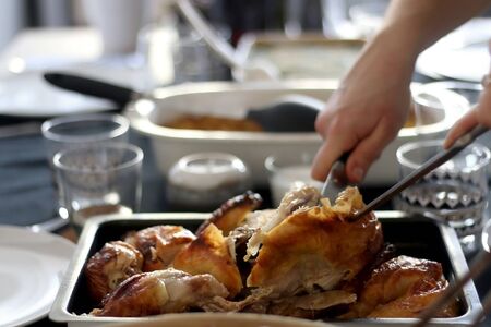 Cutting up a whole roast chicken on a table. Lunch for friends and family. Selectve focus.の写真素材