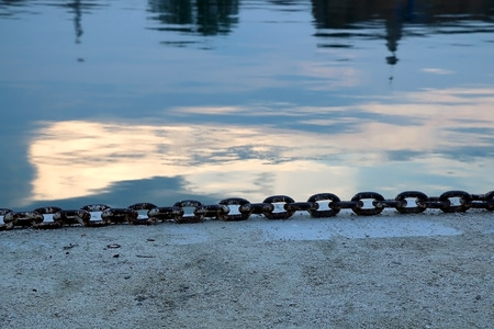Big nautical chain on the shore during blue hour. Selective focus.
