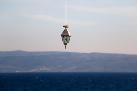 Retro lantern hanging outdoor. Beautiful bright blue sea and sky in the background.の写真素材