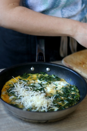 Unrecognizable person making frittata with chicory and cheese. Selective focus.の写真素材