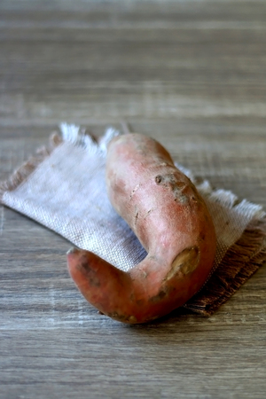 Raw sweet potato on a wooden table. Selective focus.の写真素材