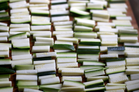 Chopped zucchini pieces on a wooden cutting board. Top view, selective focus.の写真素材