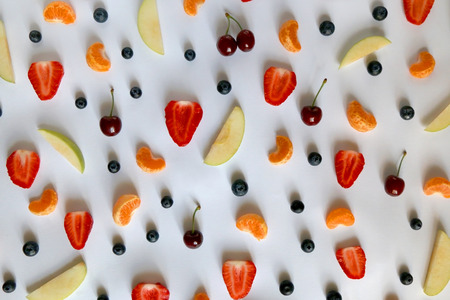 Various fruits and fruit slices on white background: apple, strawberry, banana, blueberry, cherry and tangerine. Top view, flat lay.の写真素材
