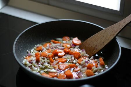 Roasting carrot and onion on olive oil. Selective focus.